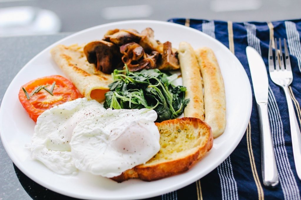 Plato con huevo, salchichas, tomate, espinacas y pan